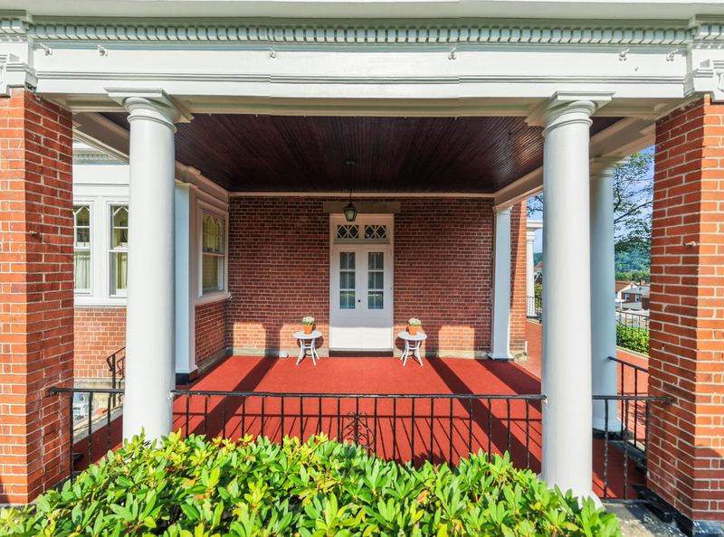 Columned wrap-around porch with brick floor